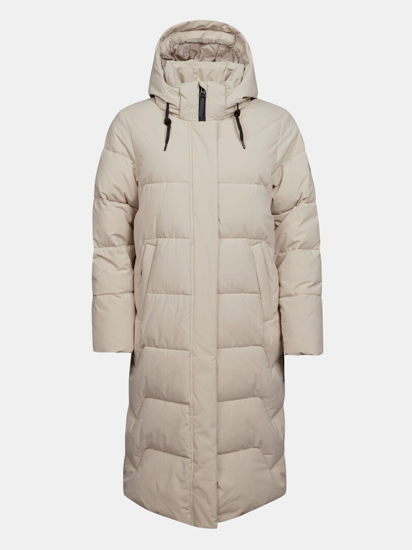 Die „Halti Brahe Puffer Long Winterjacke Damen“ ist eine beige, wattierte Jacke mit Kapuze, Reißverschluss vorne und zwei großen Taschen.