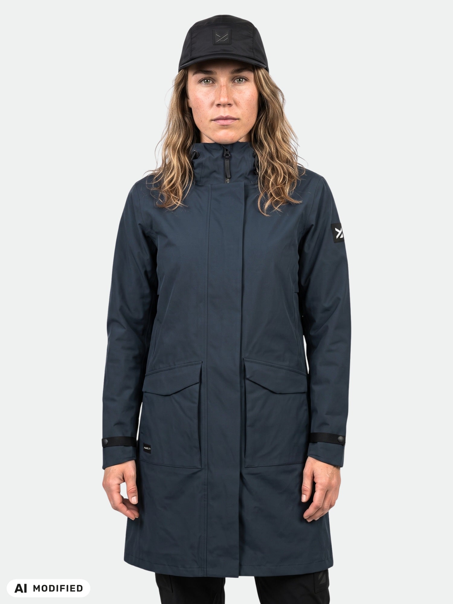 Eine Frau in einer „Tokoi II DX“-Parkajacke von Halti mit DrymaxX®-Außenmaterial blickt vor einem hellen Hintergrund in die Kamera.