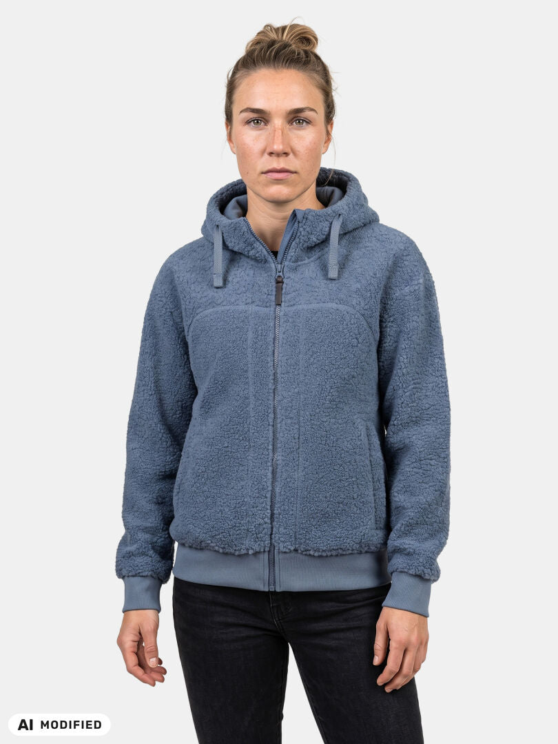 Eine Person, die eine blaue Halti Lykky Fleece-Jacke für Damen trägt, steht mit dem Gesicht nach vorne vor einem schlichten weißen Hintergrund.