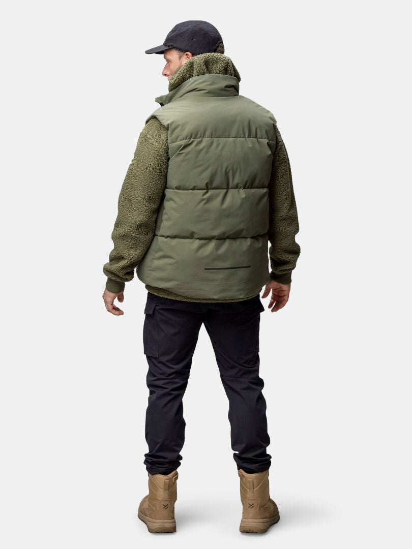 Ein Mann in der Halti Penger Classic Puffer Weste, schwarzer Hose und Mütze von hinten gesehen.