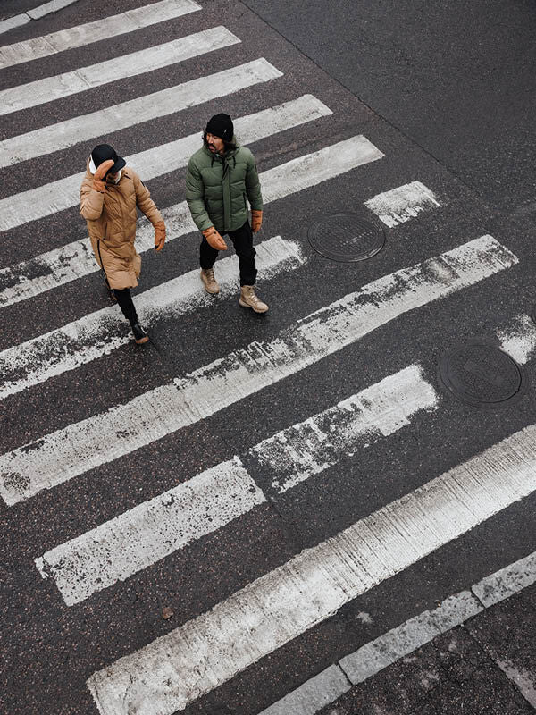 Zwei Personen in Halti Brahe Puffer Long Winterjacke Damen überqueren eine Stadtstraße, von oben gesehen.