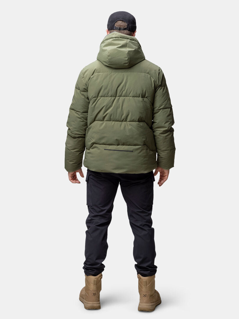 Ein Mann trägt die Halti Brahe Puffer Winterjacke aus recyceltem Polyester, schwarze Hose und Kappe, Rücken zur Kamera.