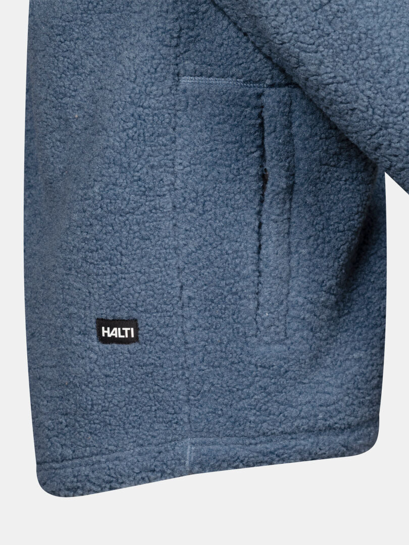 Nahaufnahme einer blauen Halti Lykky Fleece-Jacke für Herren mit Tasche und einem kleinen schwarzen Halti-Logo-Etikett am Saum.