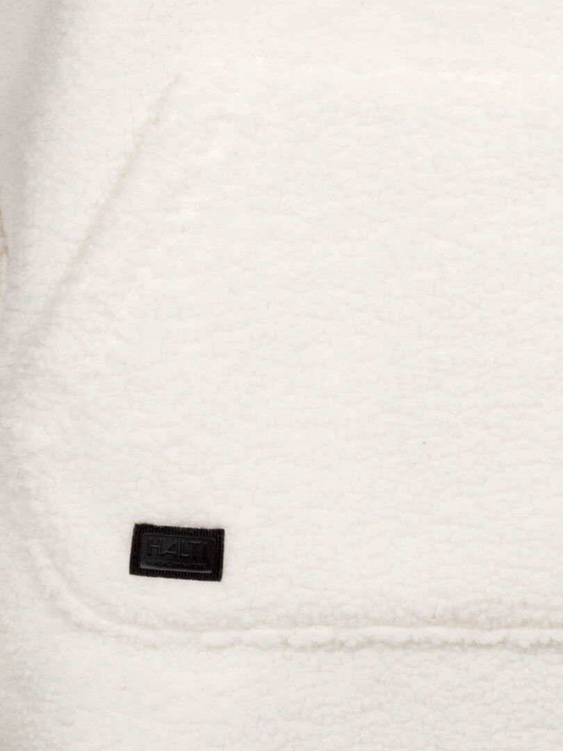 Nahaufnahme eines weißen Lykky Fleecepullover Damen mit aufgenähtem schwarzem Halti-Label in der linken unteren Ecke.