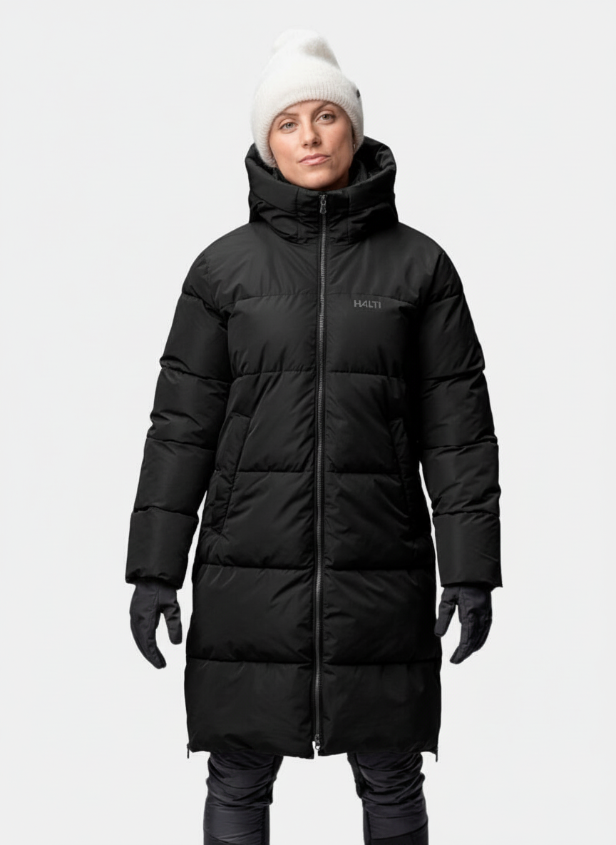 Person in einem Halti Sammal Isolationsparka Damen, weißer Mütze und Handschuhen steht mit dem Gesicht nach vorne vor einem schlichten Hintergrund.