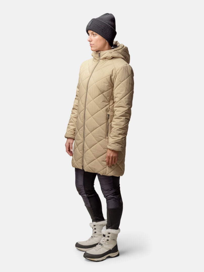 Person in einem beigen Halti Haapa Steppmantel Damen, schwarzen Leggings, grauen Winterstiefeln und einer schwarzen Mütze, seitlich stehend.