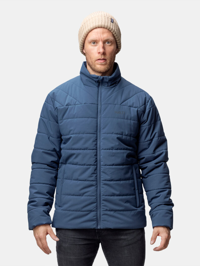 Ein Mann in einer Halti Haapa Steppjacke Herren steht vor einem schlichten weißen Hintergrund.