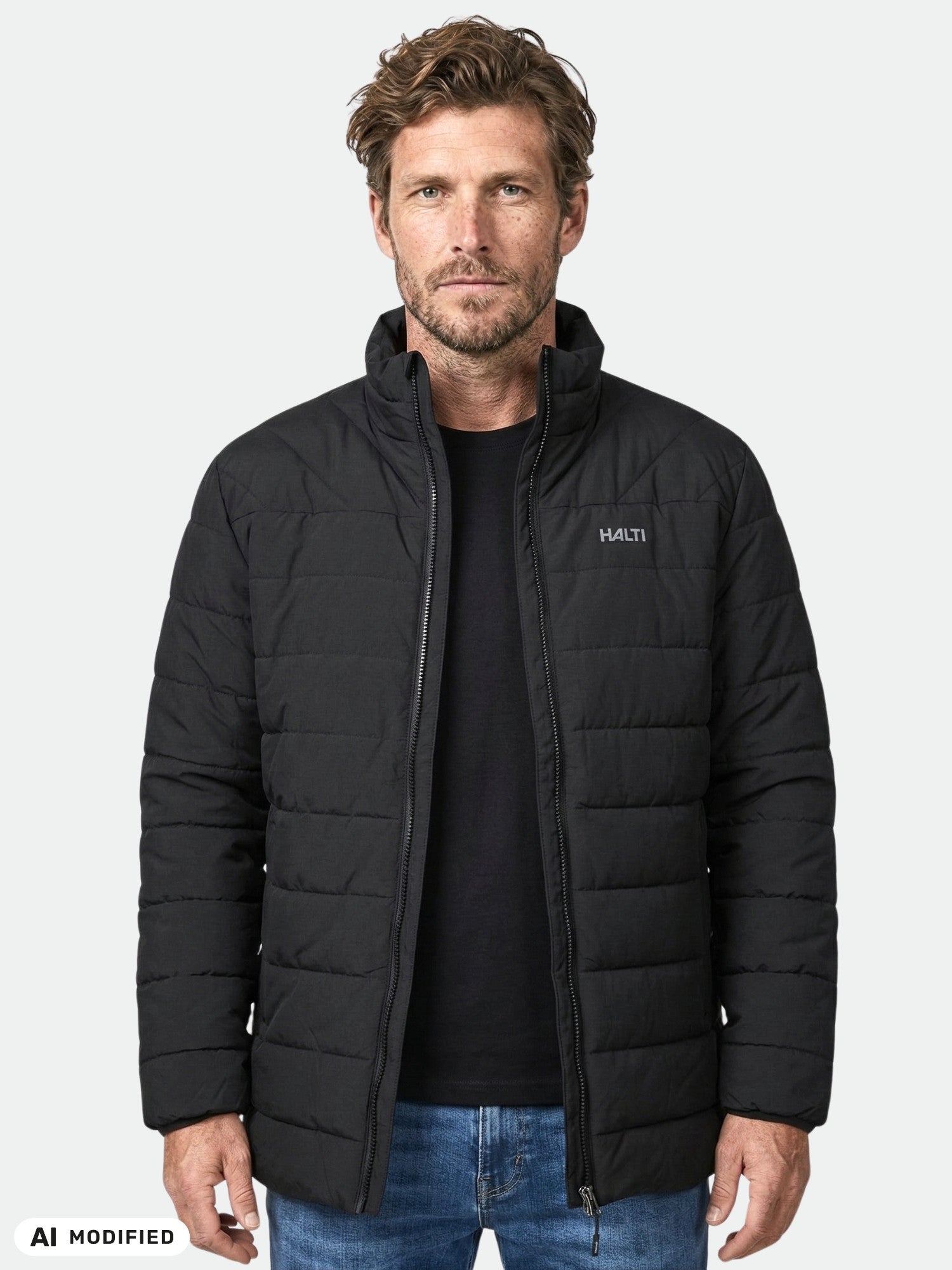 Ein Mann in einer schwarzen Halti Haapa Steppjacke für Herren steht vor einem schlichten, hellen Hintergrund.