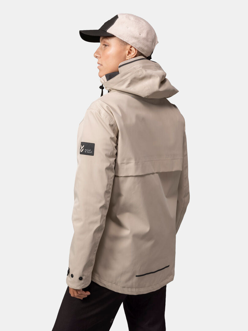 Frau in der wetterfesten Tokoi DX Jacke von Halti und zweifarbiger Cap seitlich vor neutralem Hintergrund.