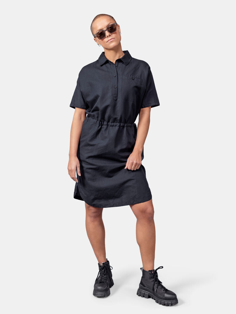 Eine Frau trägt das Halti Notsgi Kleid Damen aus Hanf und Bio-Baumwolle mit schwarzen Boots und Sonnenbrille.