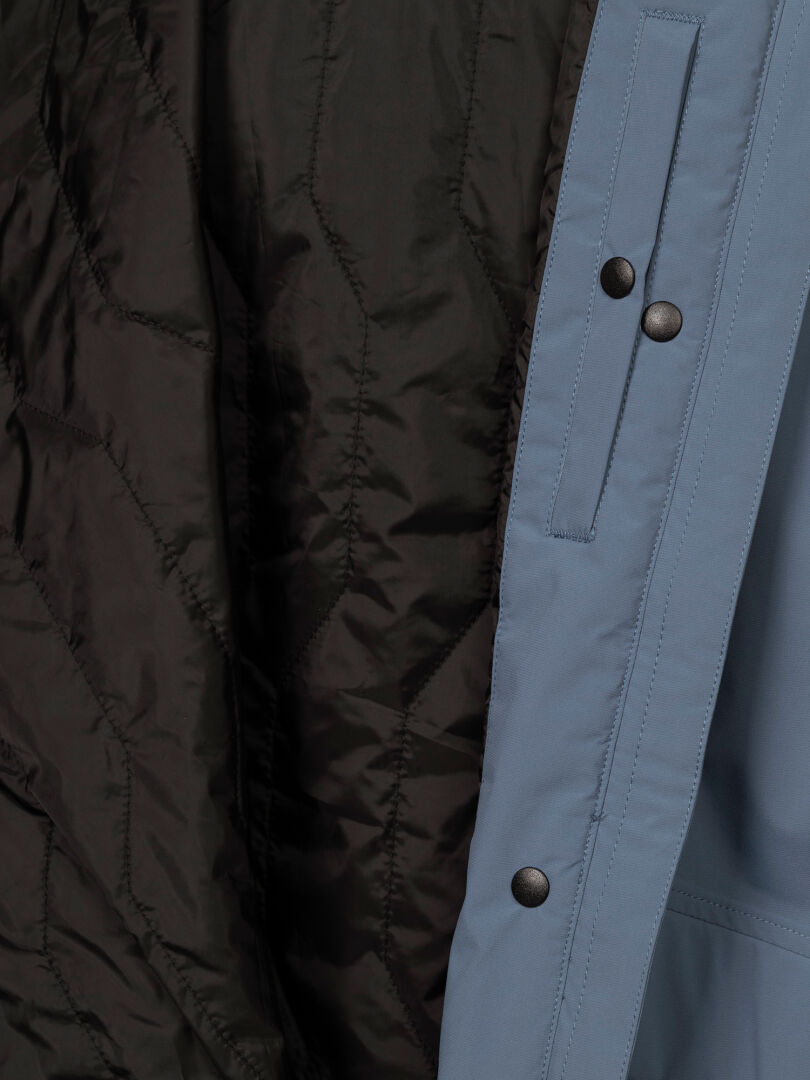 Nahaufnahme des Halti Kortteli DX Insulated Parka für Damen mit gestepptem schwarzem Futter, blauem Obermaterial und Druckknöpfen.