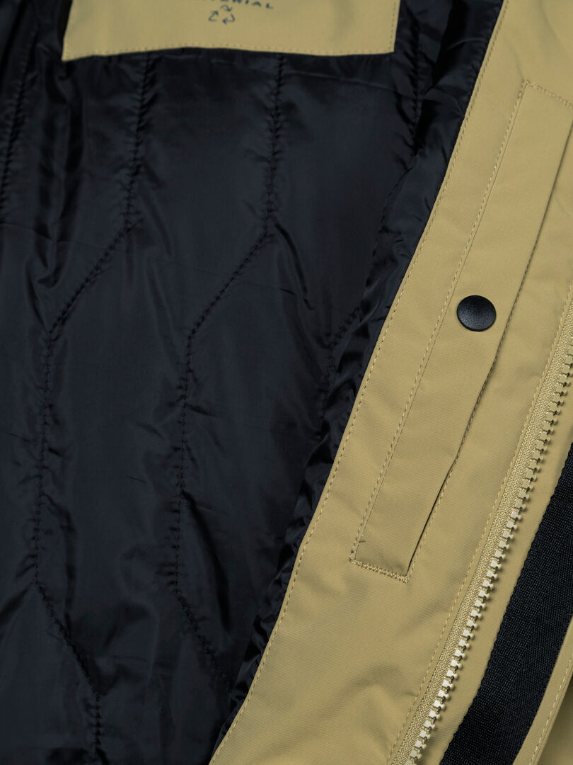 Nahaufnahme des Halti Kortteli DX Insulated Parka für Herren: beiges, gestepptes Futter, Reißverschluss, Druckknopf und teilweise sichtbares „Wetterschutz“-Etikett.