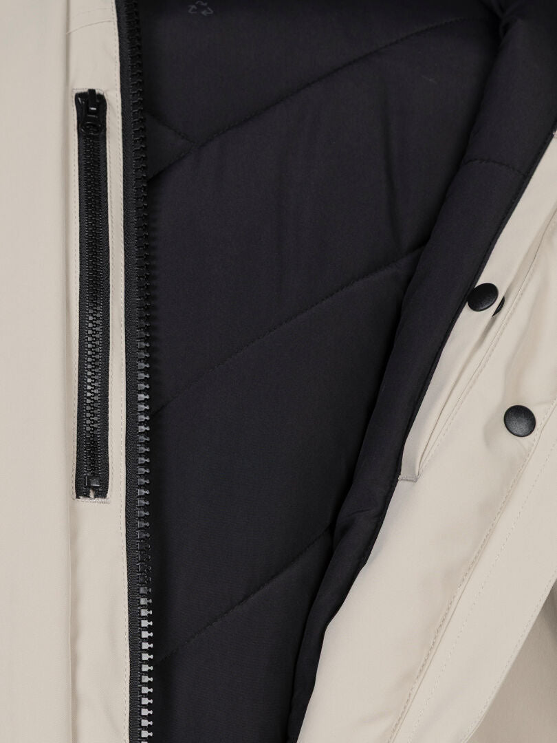 Nahaufnahme des „Halti Kallio DX Parka Damen“ in Beige mit schwarzem Reißverschluss und gestepptem Microtherm-Futter.