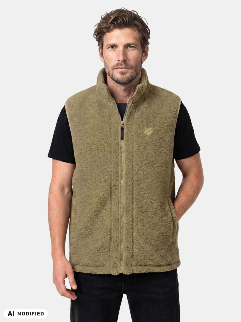 Ein Mann, der eine Halti Lykky Fleece-Weste (Unisex) über einem schwarzen T-Shirt trägt und vor einem einfarbigen Hintergrund steht.