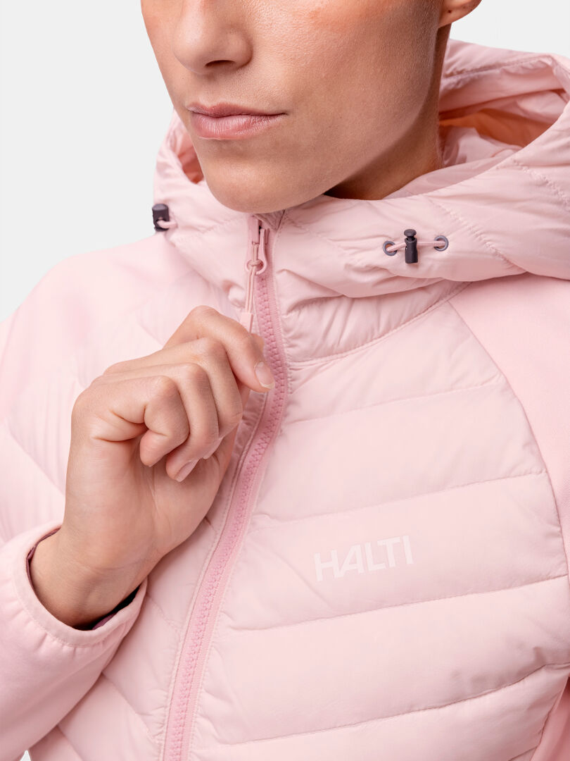Person, die eine hellrosa Halti Huippu Hybrid Daunenjacke Damen mit Kapuze hochzieht; Pertex Quantum Ripstop, Logo auf der Brust.