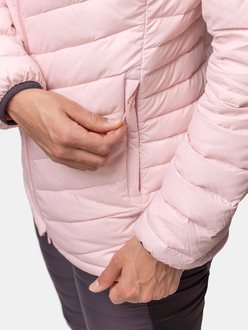 Eine Frau, die mit einer Hand die Tasche einer hellrosa Halti Huippu Mid Daunenjacke zuzieht und sie mit der anderen hält.