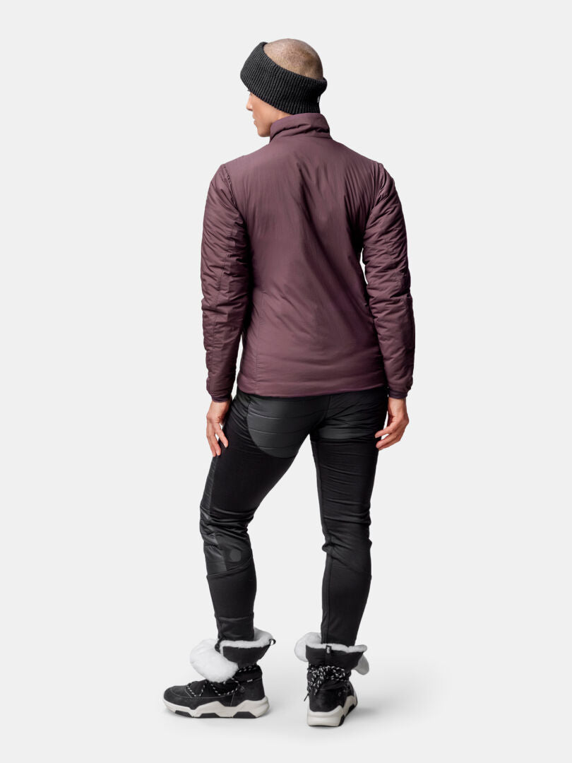 Person steht mit dem Rücken zur Kamera und trägt eine violette Halti Haave Insulation Primaloft Jacke Damen, eine schwarze Hose und Winterstiefel.