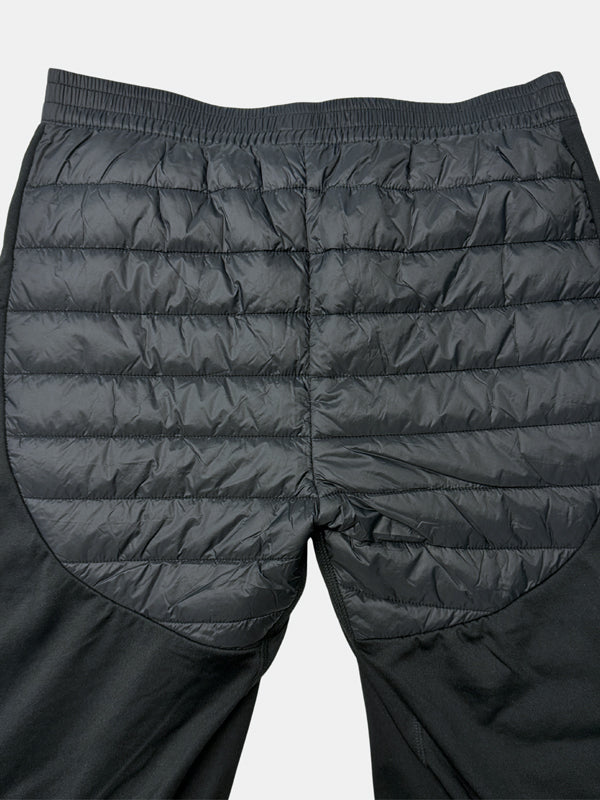 Die Halti Veidnes Insulation Hosen Damen Plus, schwarz, hat einen gesteppten, gepolsterten Rücken und Oberschenkel, flach liegend dargestellt.