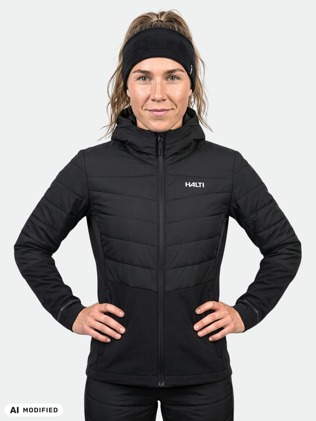 Frau, die eine schwarze Halti Valimo Hybrid Insulation Jacke Damen mit Kapuze und gesteppten Einsätzen trägt.