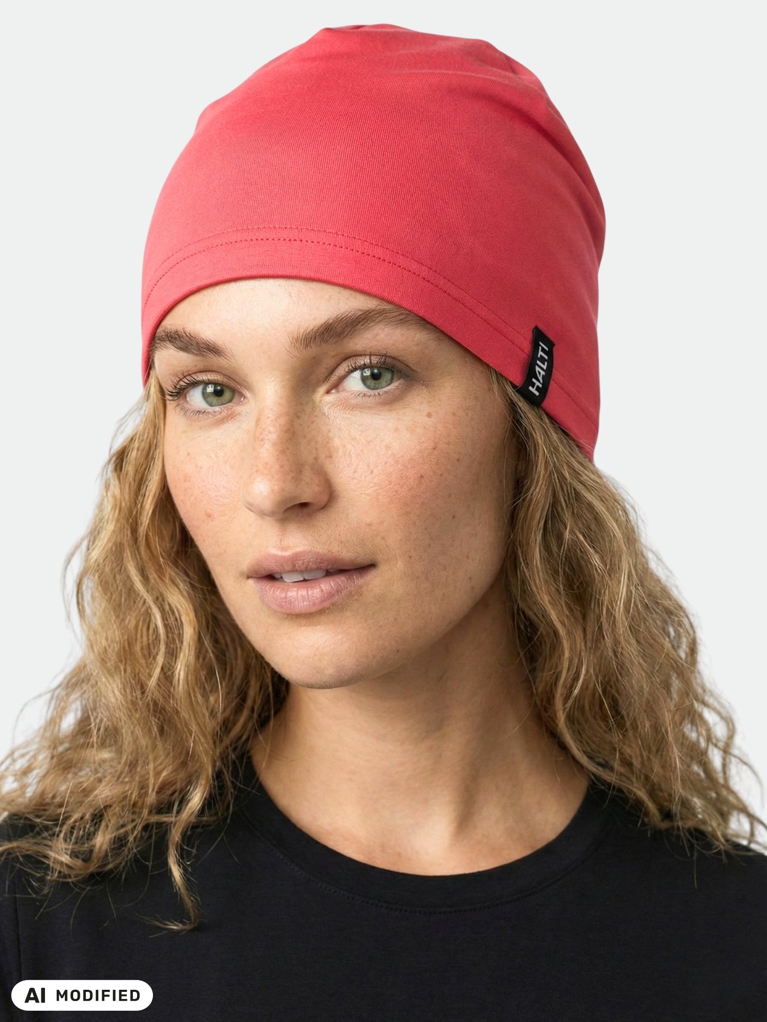 Eine Person mit welligem blondem Haar trägt eine rosa Halti Loiva-Mütze und ein schwarzes Shirt und blickt in die Kamera.