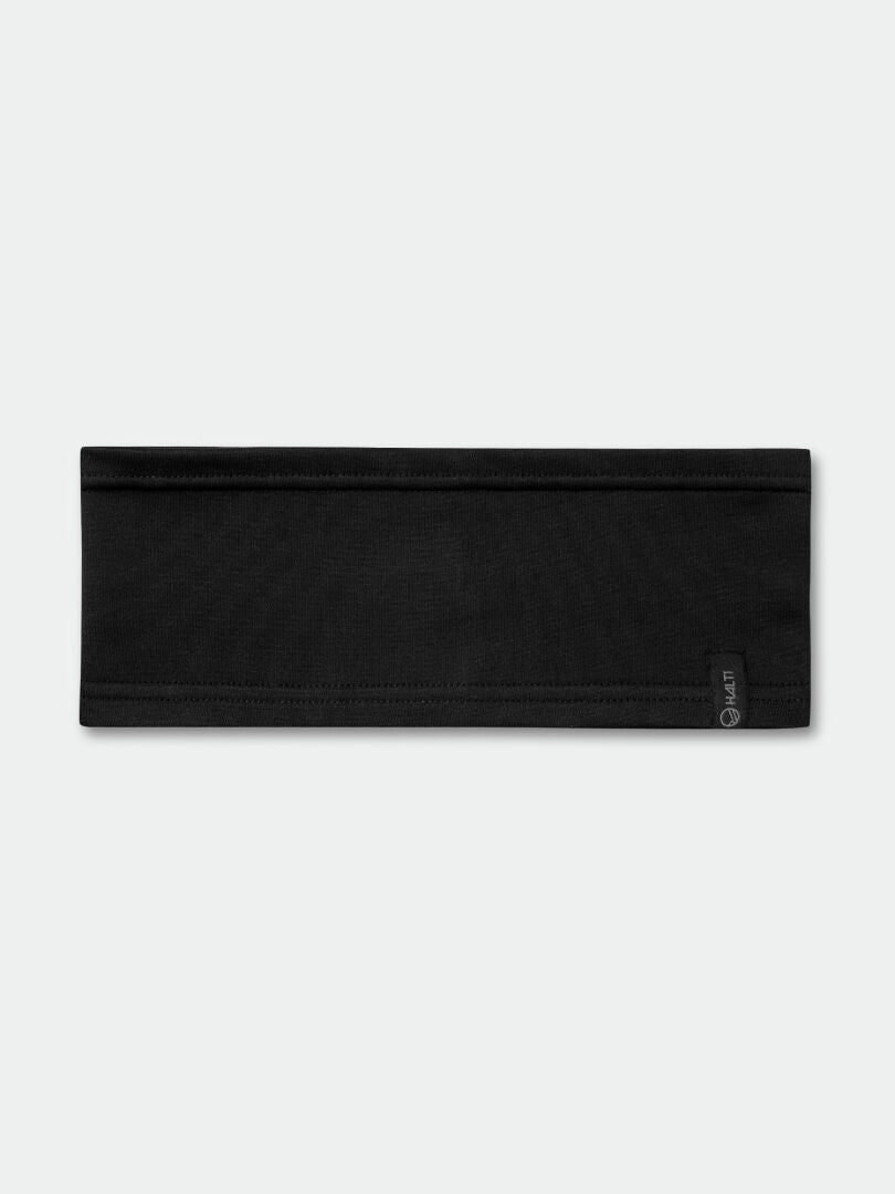 Das Halti Loiva Band ist ein flaches, schwarzes Active Dry Jersey Stirnband mit einem kleinen Anhänger auf hellem Grund.
