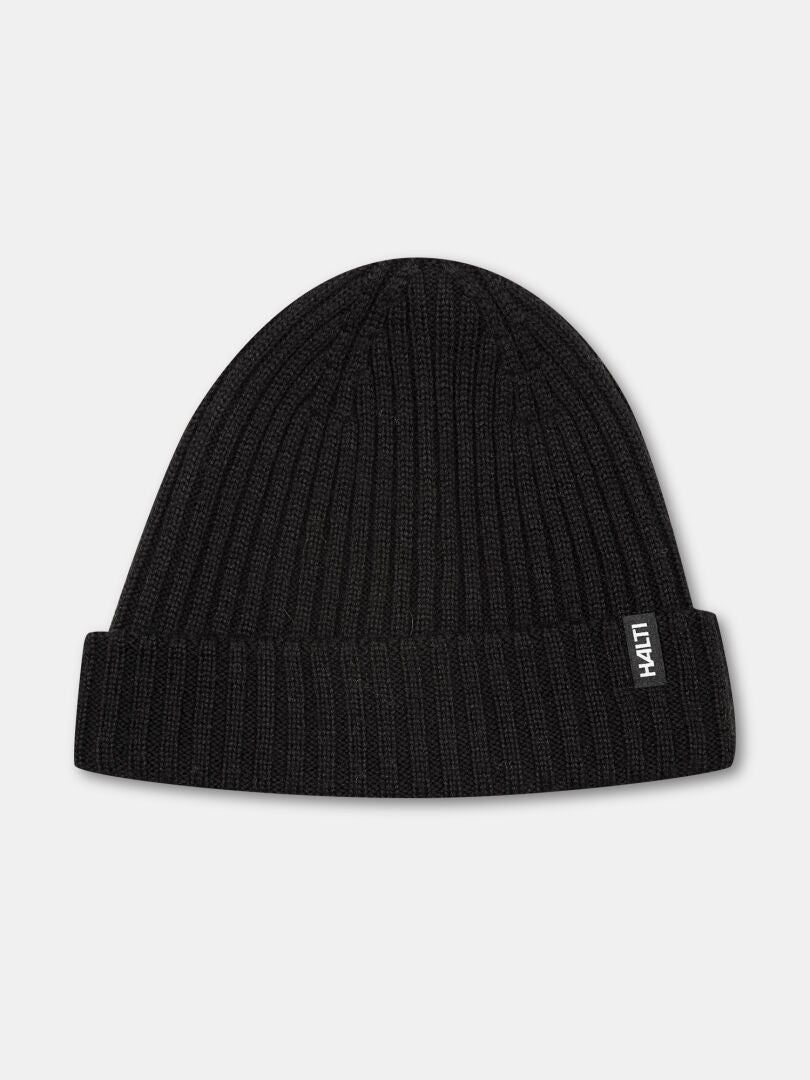 Die Halti Runko Mütze ist eine schwarze Rippenstrickmütze mit umgeschlagener Krempe und einem kleinen weißen Seitenetikett.