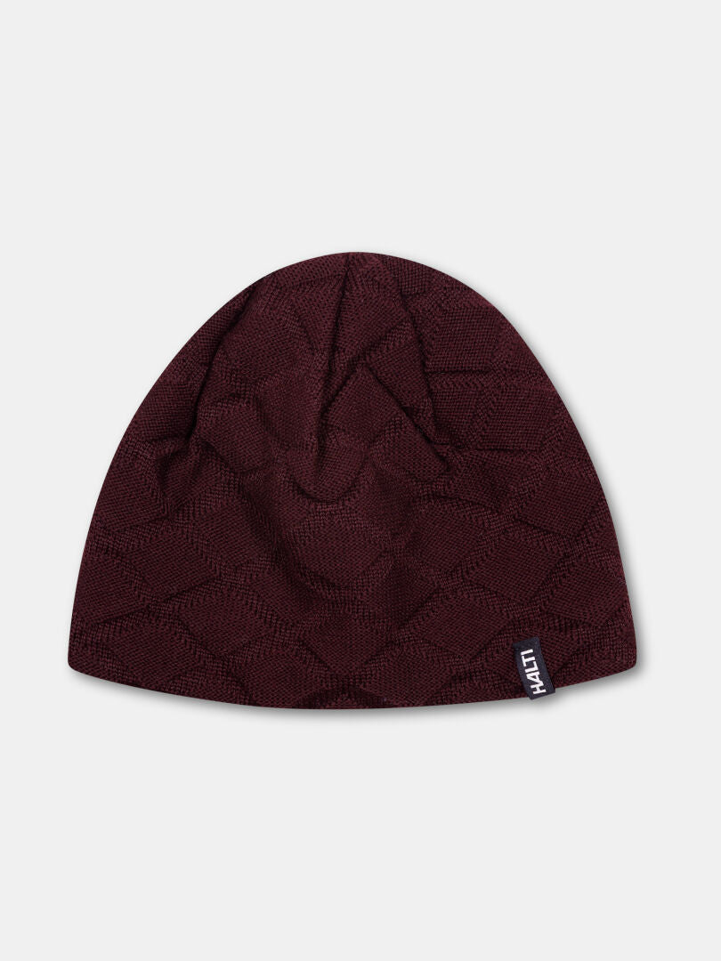 Die Halti Crostie Merino Mütze ist eine dunkelkastanienbraune Strickmütze mit dezenter Struktur und kleinem schwarz-weißem MATTI-Tag.