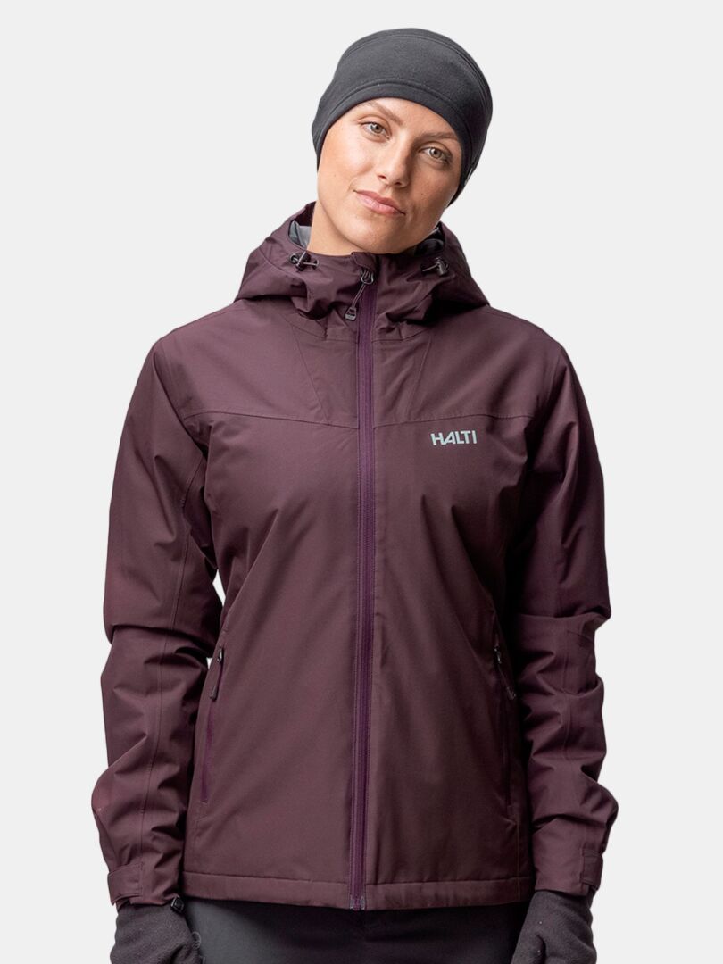 Eine Person in einer kastanienbraunen Kapuzenjacke und grauem Halti Trone Fleece Band steht vor einem hellen Hintergrund.