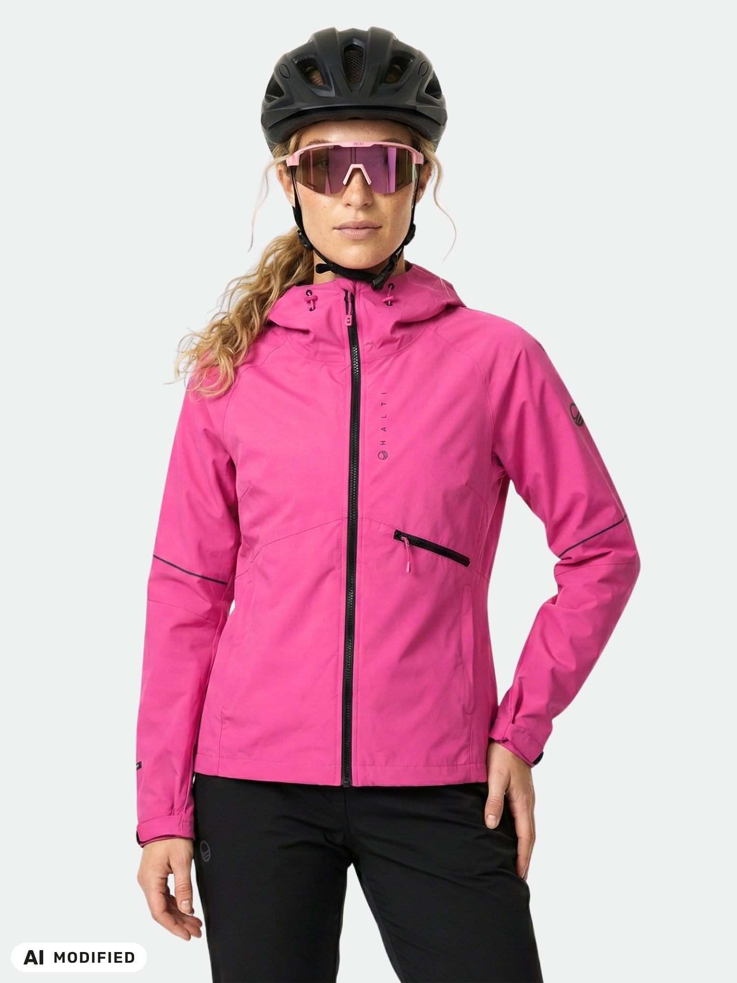 Frau in einer „Halti Shelter Stormwall 3L“-Jacke, schwarzer Hose, Helm und Sonnenbrille – ideal zum Radfahren im Winter.