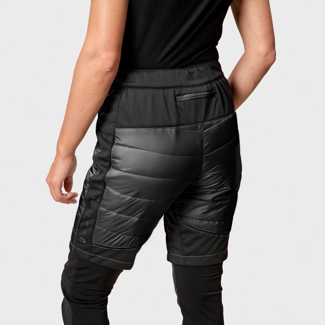 Eine Person trägt Halti Hanki Warm Hybrid Shorts Damen, dargestellt von hinten vor einem unifarbenen Hintergrund.