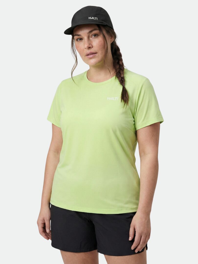Jemand trägt das Halti Salves T-Shirt Damen Plus, schwarze Shorts und eine Mütze vor einem schlichten hellen Hintergrund.