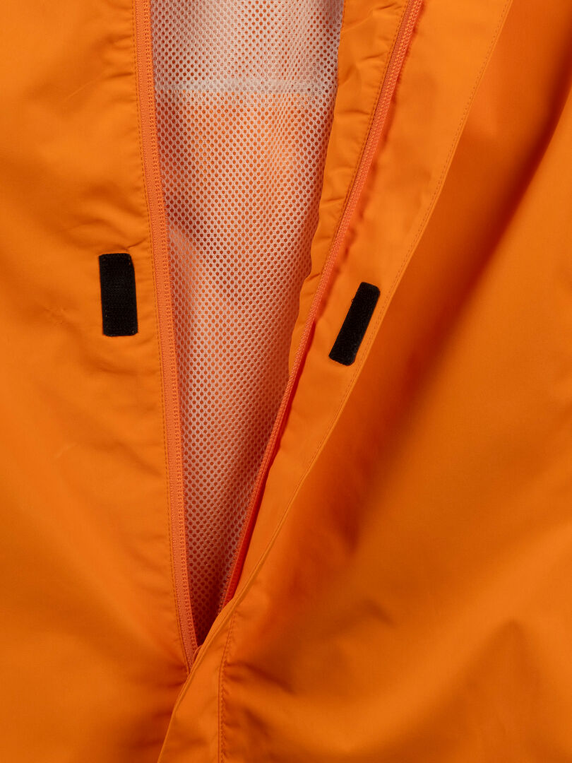 Nahaufnahme der Halti Triant DX Radjacke Herren in Orange, mit offenem Reißverschluss und weißem Netzfutter – ideal für aktive Sportarten.