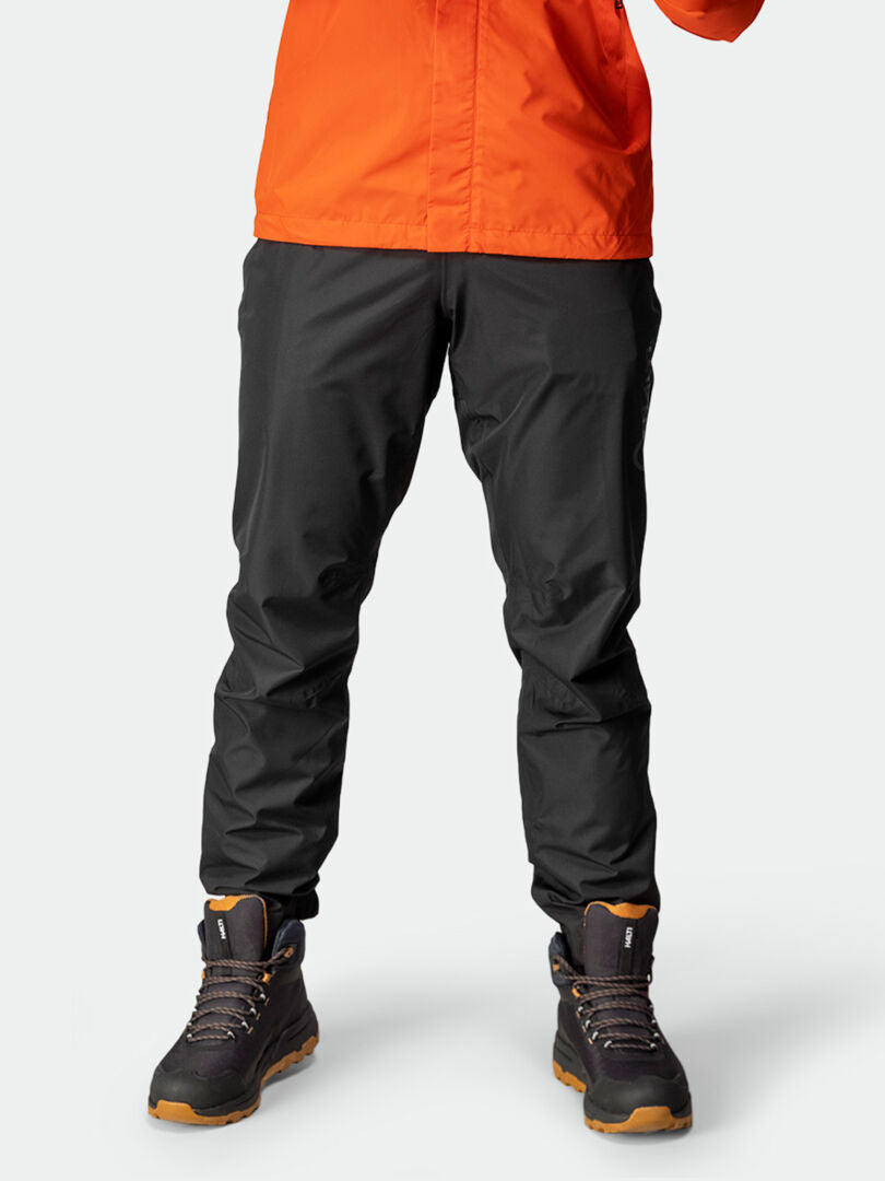 Person in Halti Triant DX Fahrradhose Herren, orange Jacke und schwarzen Wanderschuhen—Active Sport-Kollektion-Stil.
