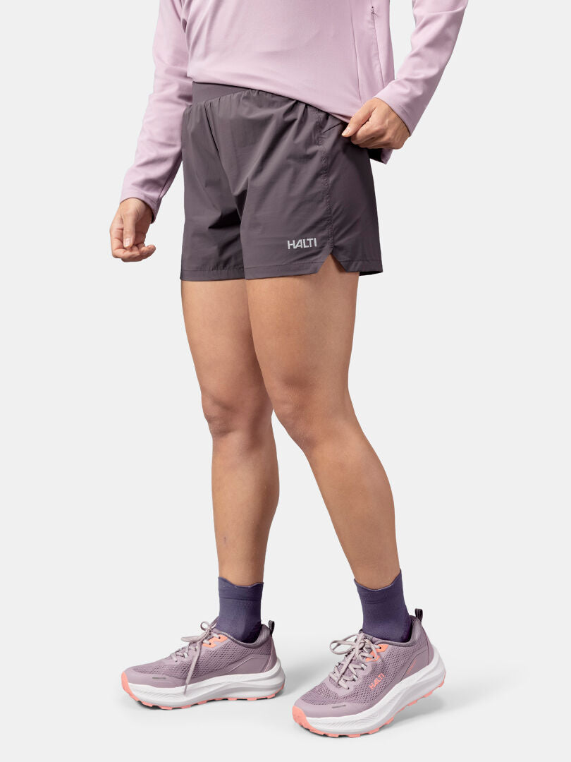 Person in einem hellvioletten langärmeligen Hemd und Halti Uurto Shorts Damen, mit passenden lila Socken und Turnschuhen.
