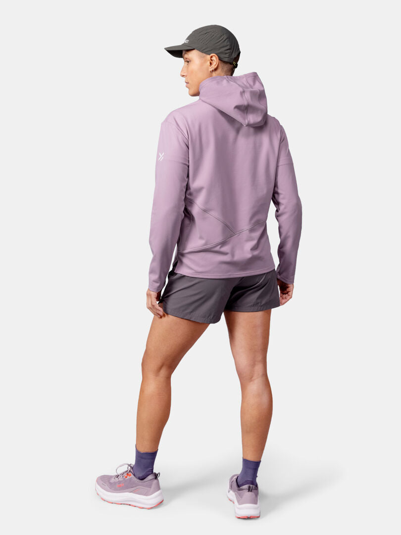 In einem Halti Kaltio Trainingshoodie Damen, grauen Shorts und Turnschuhen steht sie bereit für ein Workout im Freien und blickt nach vorne.