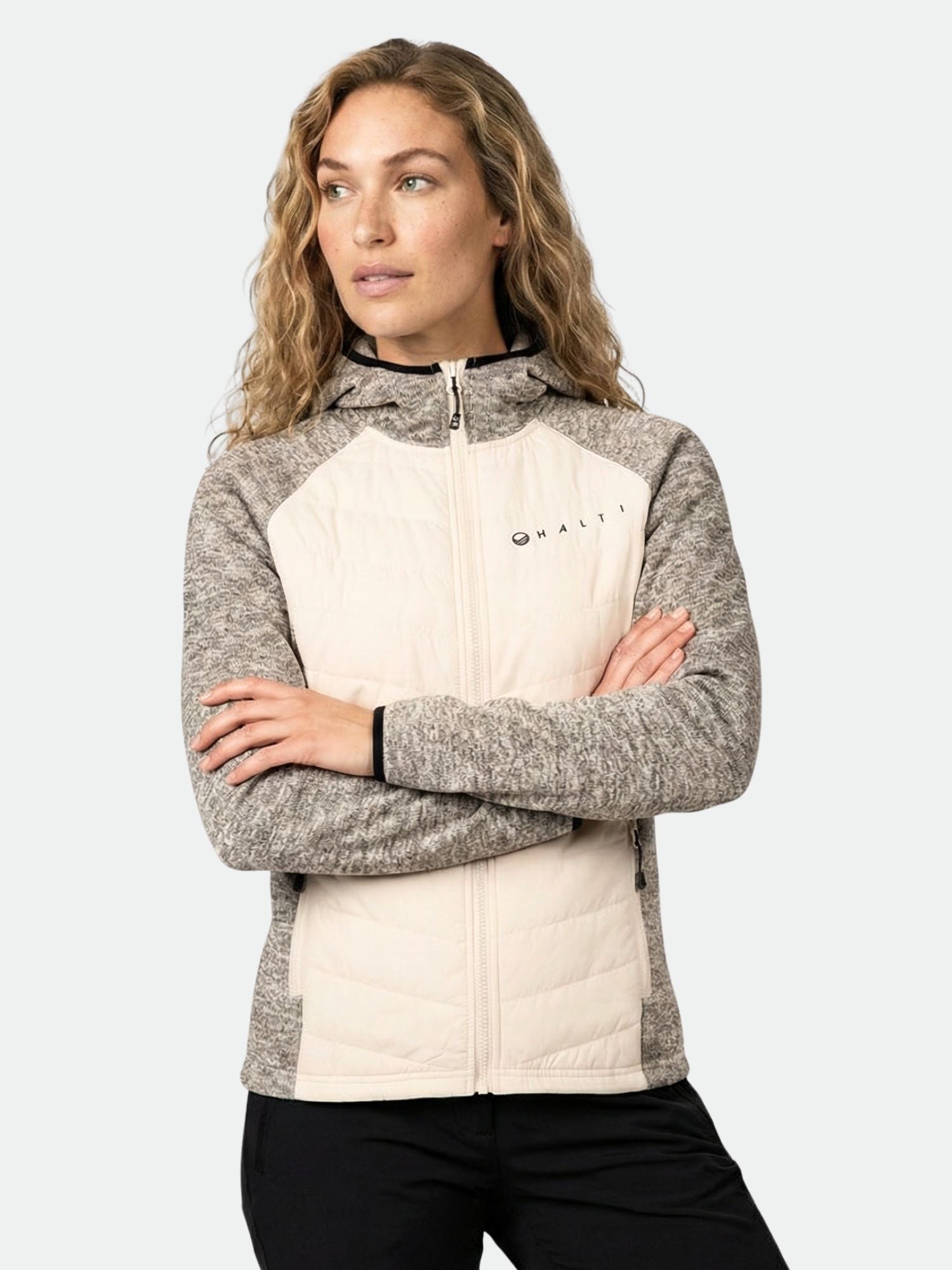 Frau mit langem gewelltem Haar in der Halti Streams Hybrid Midlayer Jacke Damen, ideal für Outdoor-Aktivitäten.