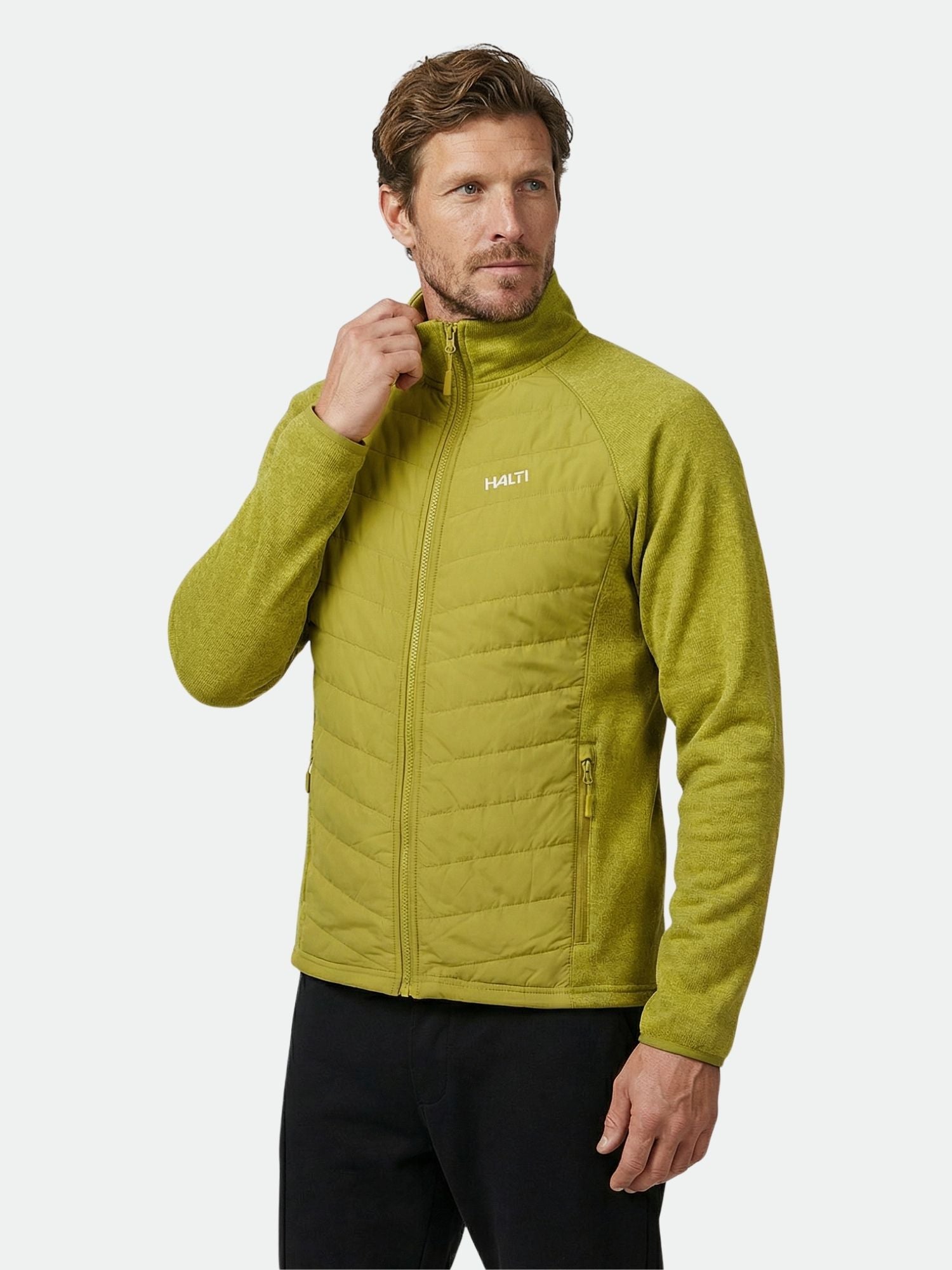 Ein Mann in einer hellgrünen Halti Streams Hybrid Layer Jacke Herren mit gesteppten Einsätzen, Logo, einfarbigem Hintergrund.