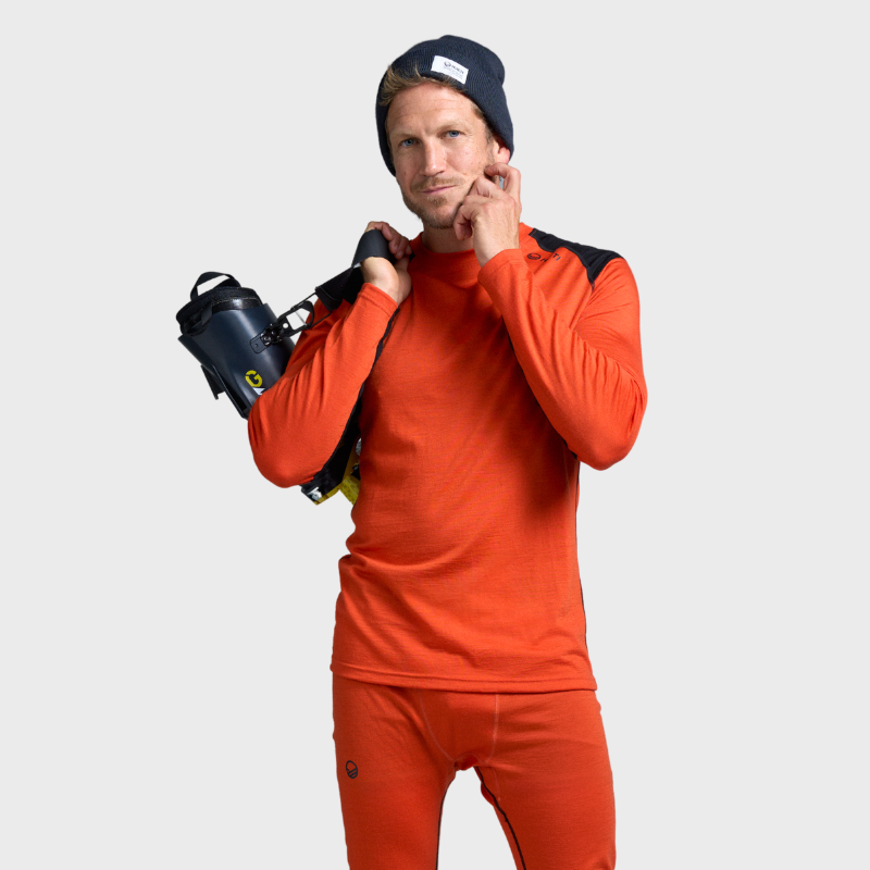 Mann in Halti Hossa Merino Unterwäsche Set Herren und dunkler Mütze mit Skistiefeln, bereit für Outdoor-Aktivitäten.