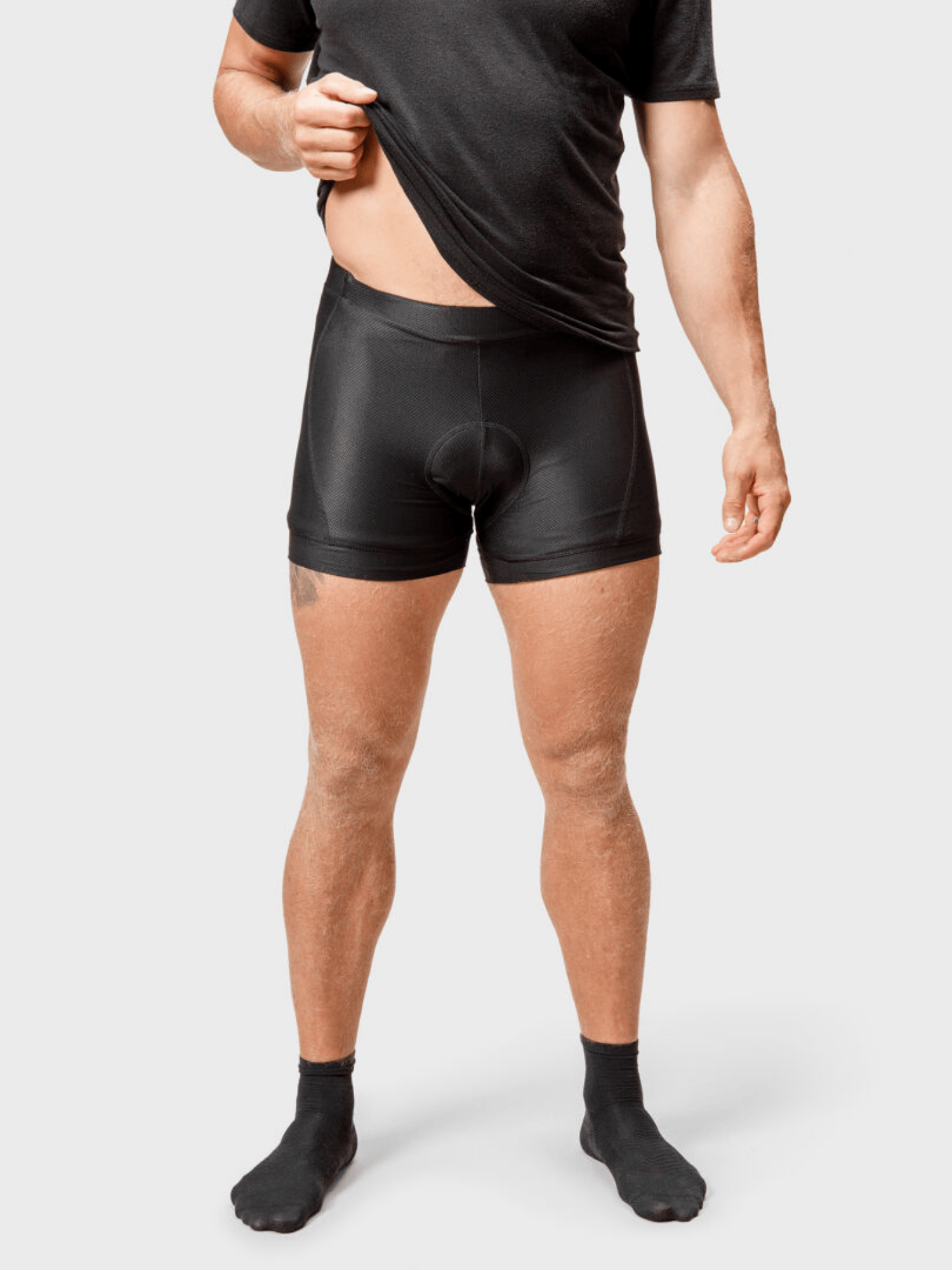 Eine Person in Halti Bike Rad Shorts Herren und schwarzen Socken hebt nach dem Radfahren ihr Hemd hoch.