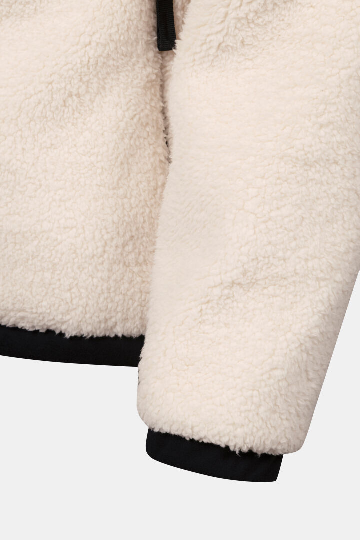 Nahaufnahme des Ärmels der Halti Lumista Polar Fleecejacke für Damen, winddicht mit schwarzem Besatz, ideal zum Wandern vor einem einfarbigen Hintergrund.