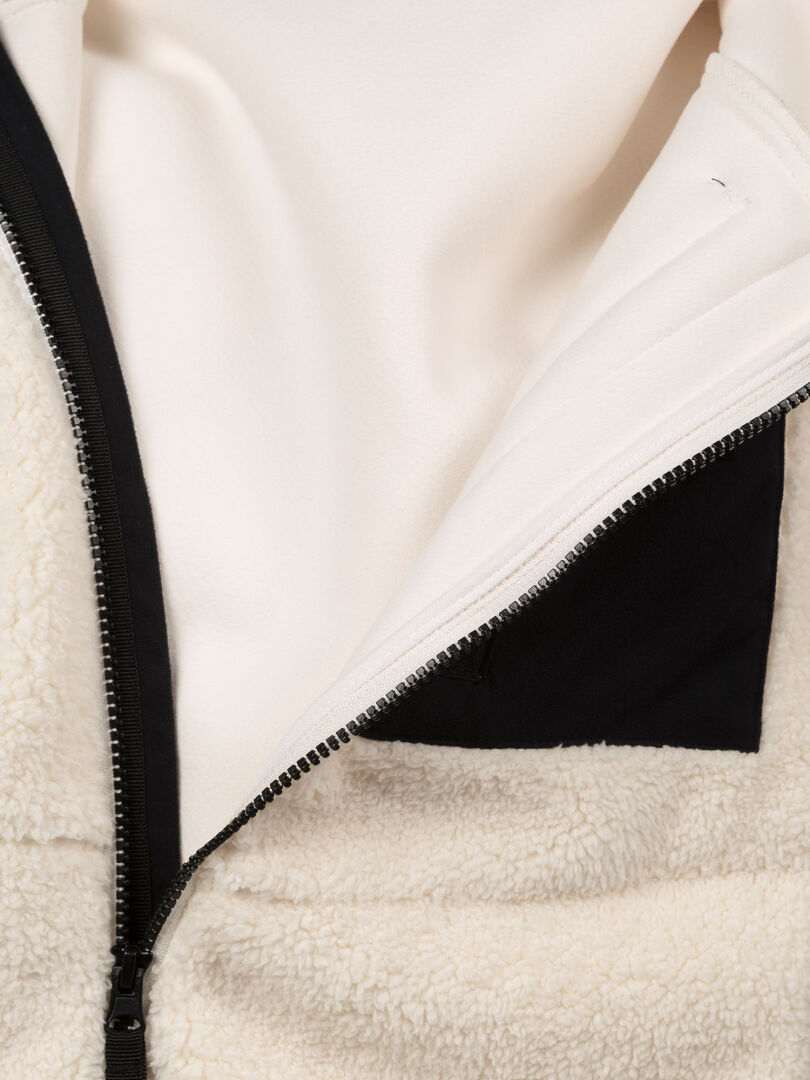 Nahaufnahme der Halti Lumista Polar Fleece Jacke Damen in creme, mit schwarzem Reißverschluss und Innentaschen-Detail.