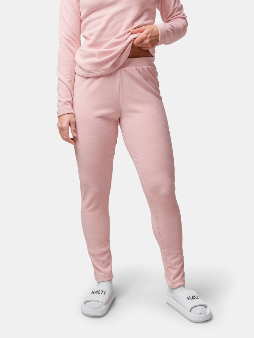 Person trägt eine hellrosa Trone Fleece-Hose Damen von Halti, ein passendes Oberteil und weiße Halti-Pantoffeln.