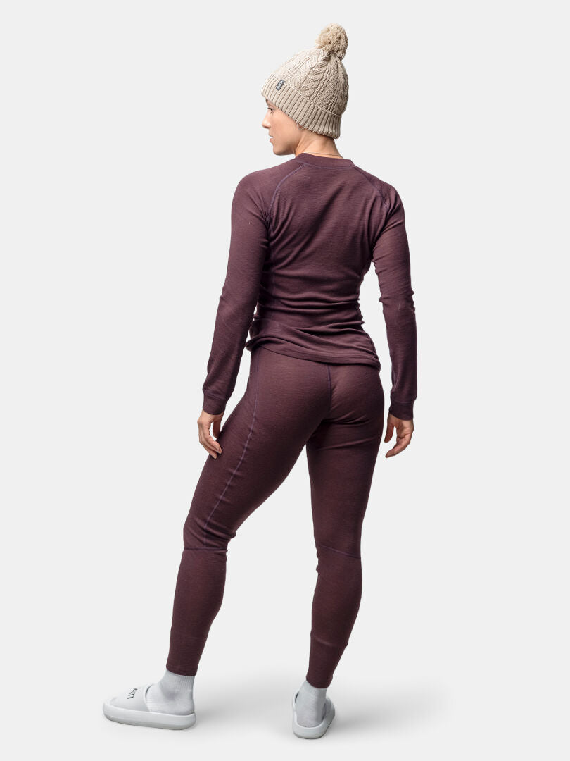 Person mit Halti Hossa II Merino Unterwäsche Set Damen, beiger Strickmütze und weißen Hausschuhen, von der Seite gesehen.