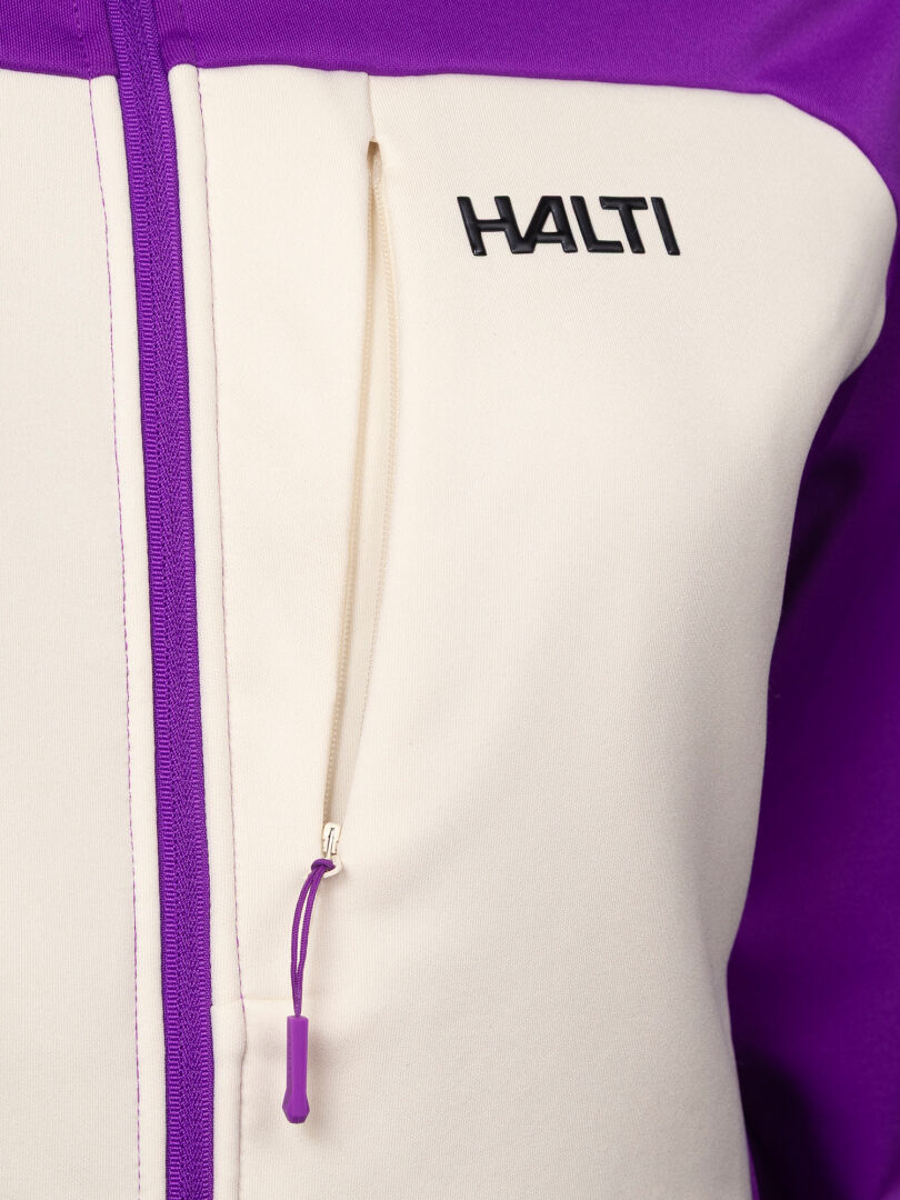 Nahaufnahme einer weiß-lila Halti Seiland Layer Jacke Damen – einer elastischen Midlayer-Jacke mit Reißverschluss, Brusttasche und Logo.