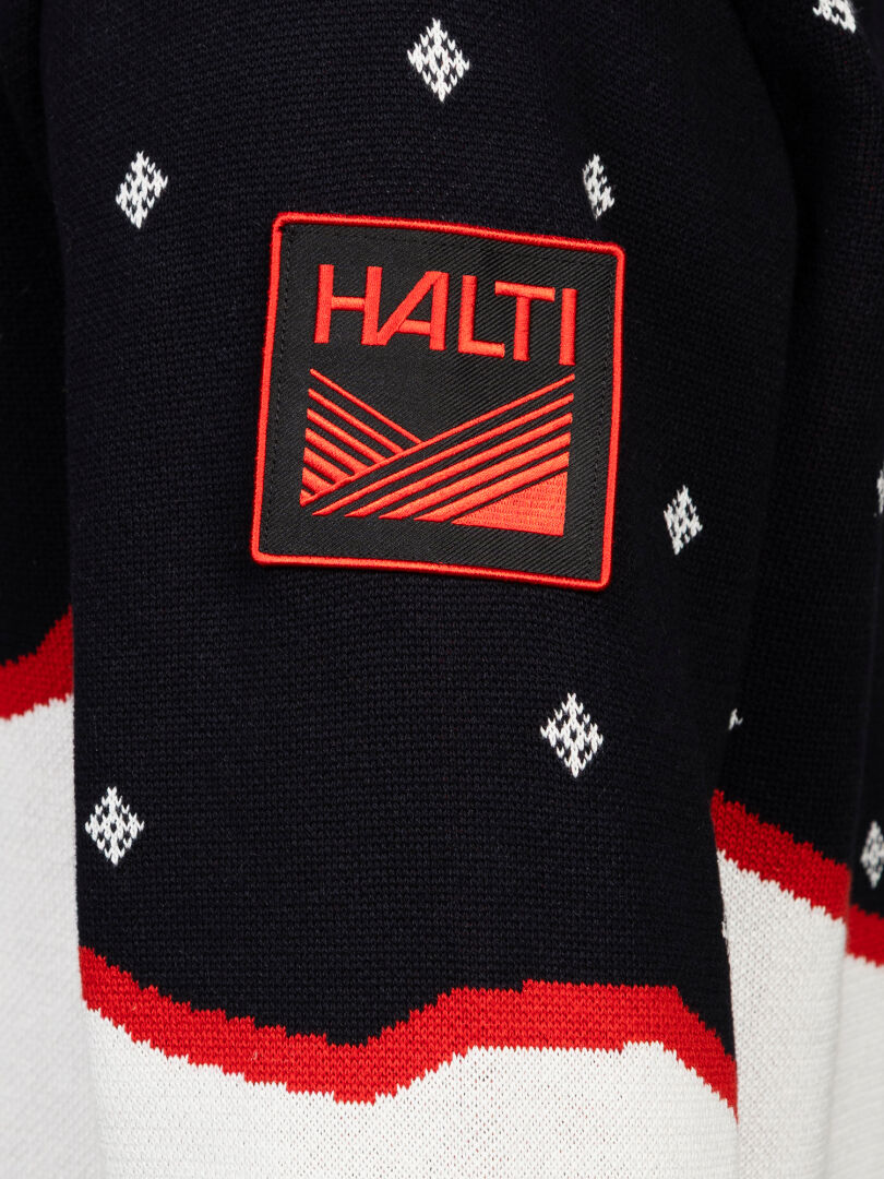 Eine Nahaufnahme eines schwarzen „Tauko Unisex“-Pullovers von Halti mit weißen Rautenmustern und einem roten HALTI-Aufnäher am Ärmel.