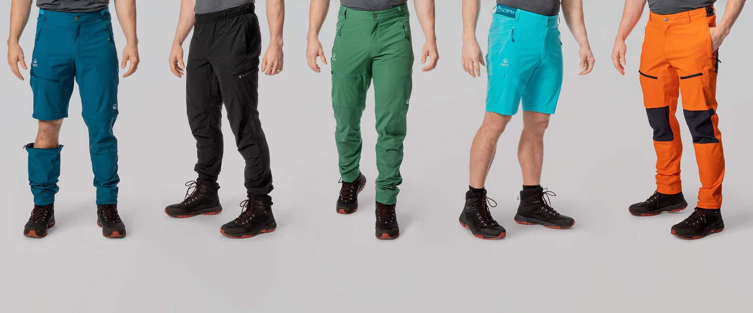 Fünf Männer in Wanderhosen und -stiefeln unterschiedlicher Art und Farbe, die nebeneinander vor einem schlichten Hintergrund stehen.