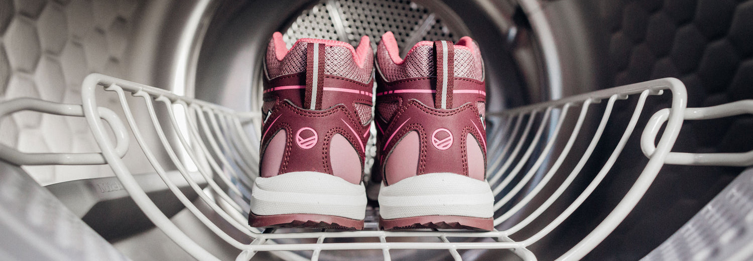 Ein Paar rosa und kastanienbraune Turnschuhe auf einem Gestell in einer Waschmaschine.