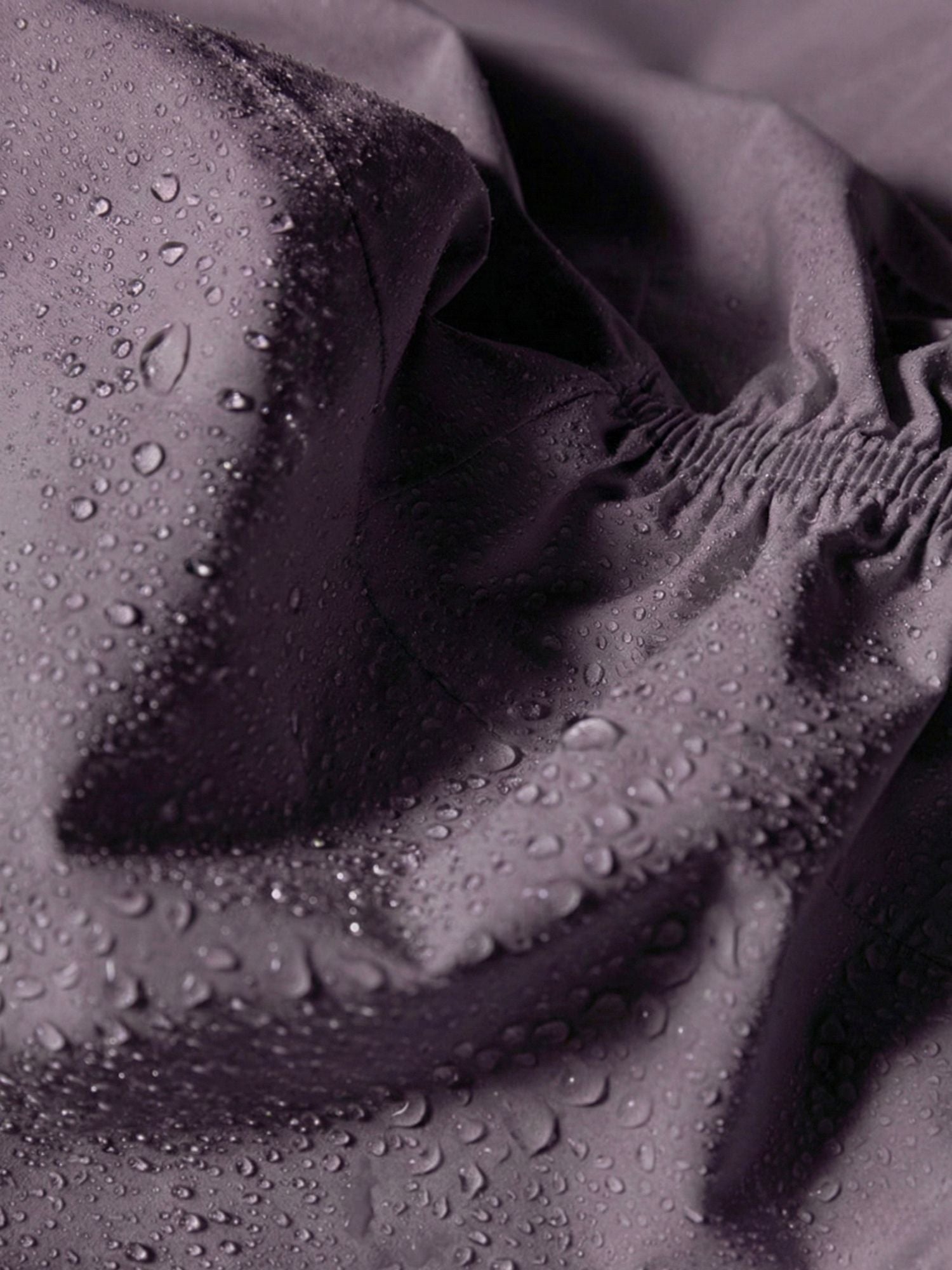 Nahaufnahme von Wassertropfen auf der Pisarat 2,5L DX Regenjacke Damen von Halti, die den wasserabweisenden Stoff hervorhebt.