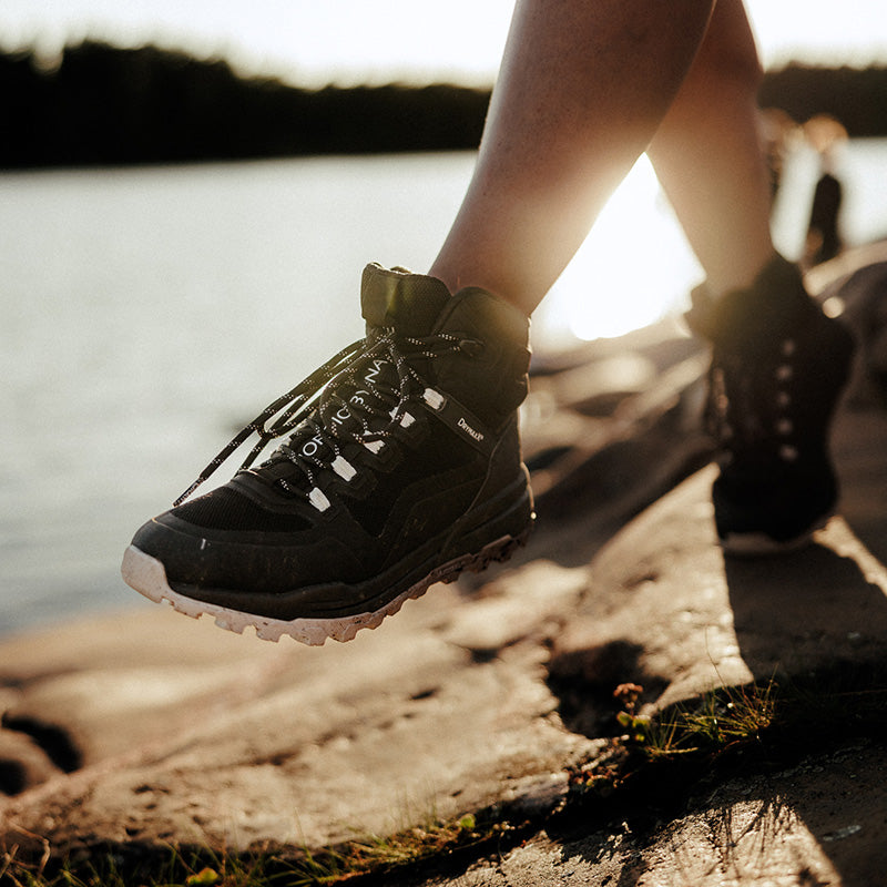Nahaufnahme der Halti Hiker Kuru DrymaxX Outdoor-Schuhe für Damen auf Felsen in der Nähe von Wasser bei Sonnenuntergang.