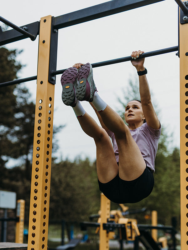 Eine Frau zieht sich in Trainingskleidung an einer Stange hoch.